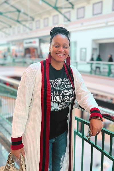 Founder Taliah Whitmire standing in a mall wearing a long cardigan and graphic Project 418 Co God Is mission tee.